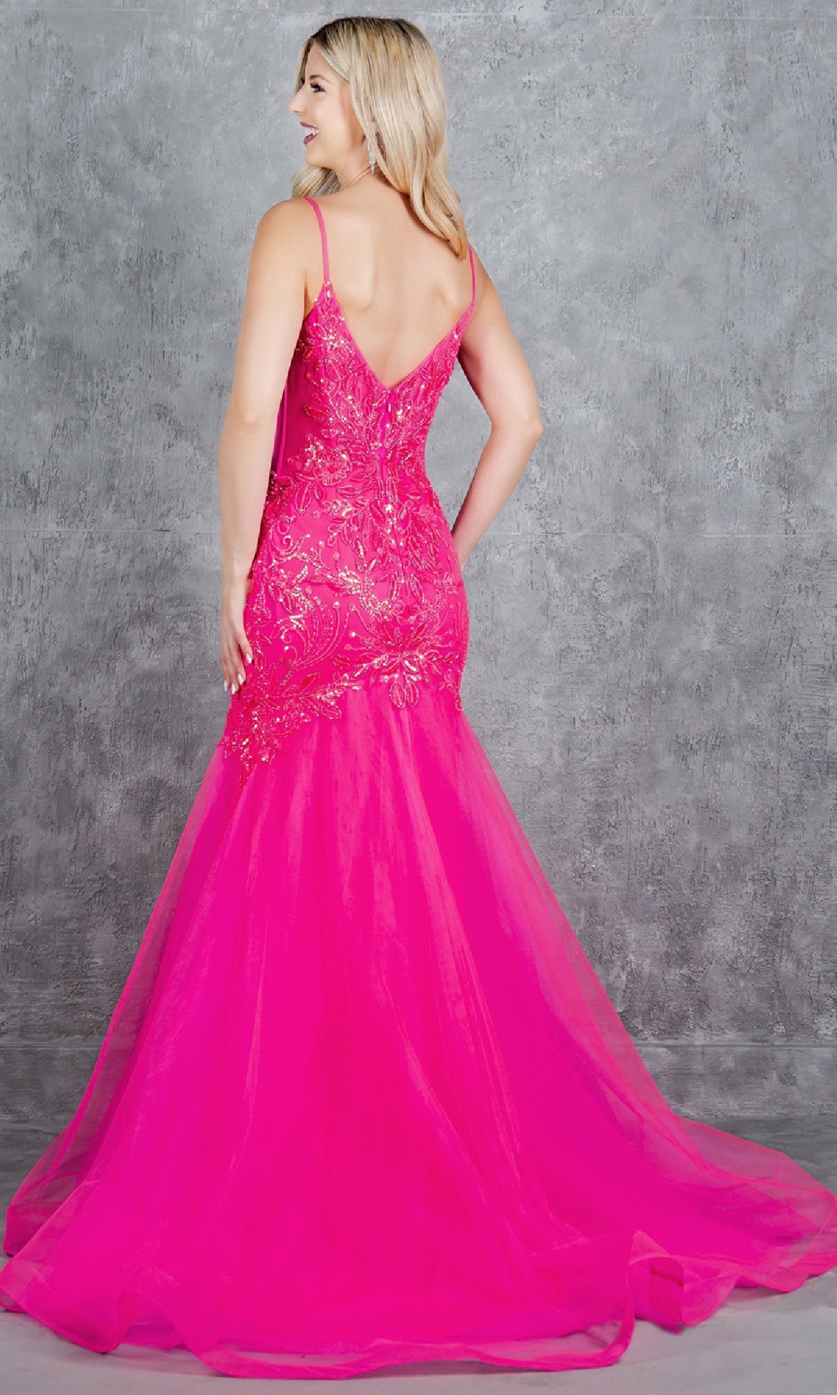 A woman faces away in the Cinderella Couture 8276J— a bright pink, floor-length mermaid prom dress with sequined floral patterns and a flared tulle skirt, perfect for special occasions.